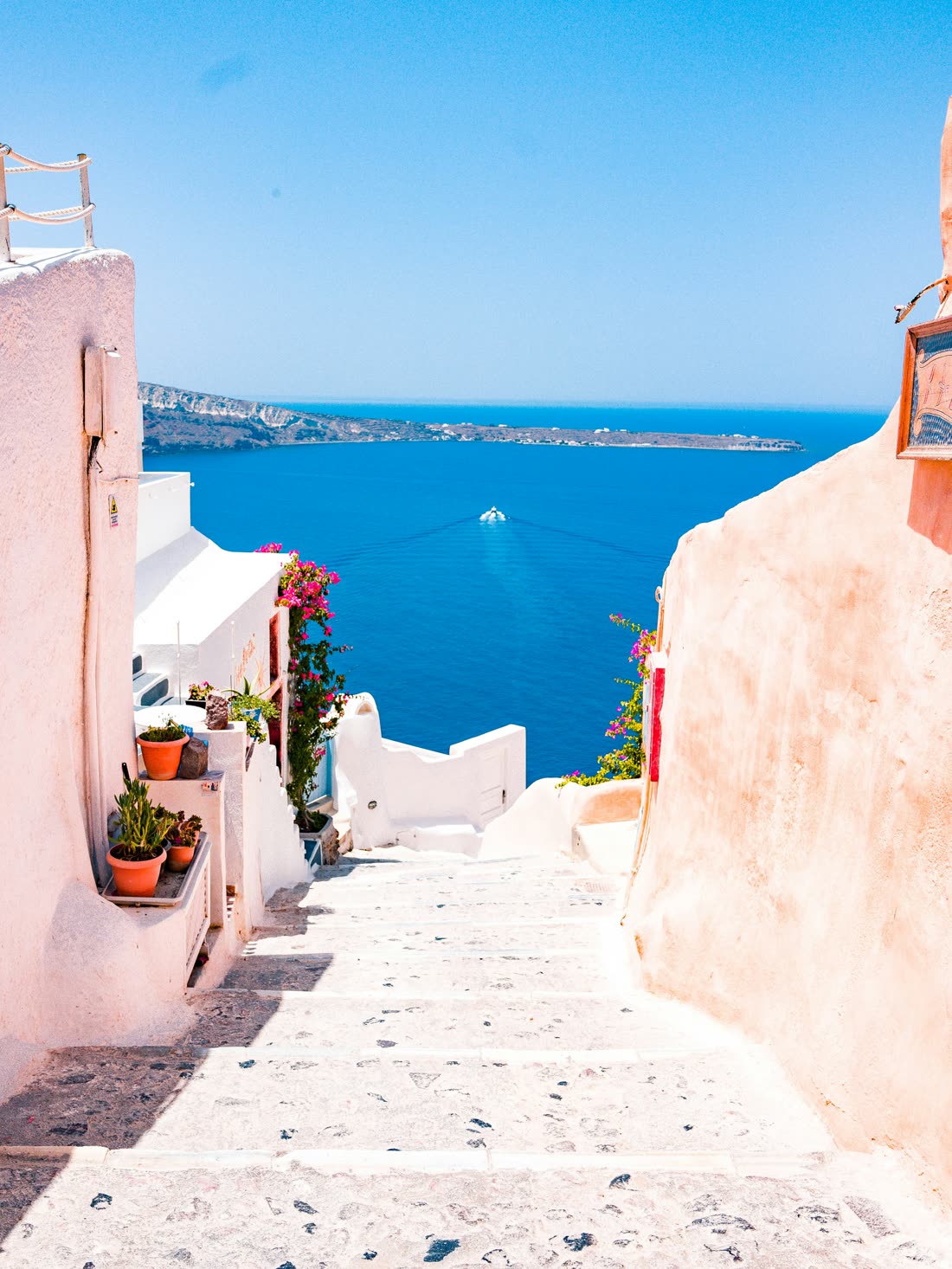 A stepped alleyway between whitewashed walls opening onto the sea